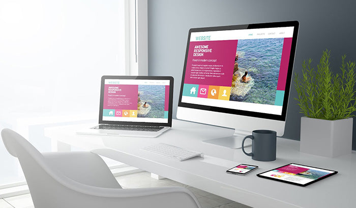 A modern desk setup with a laptop, phone, and tablet on it, showcasing software tools for the design process.