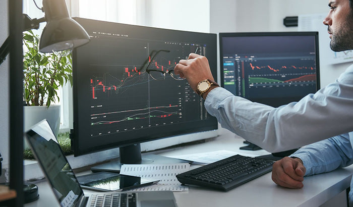  A man analyzing stock market graphs on a high-quality monitor